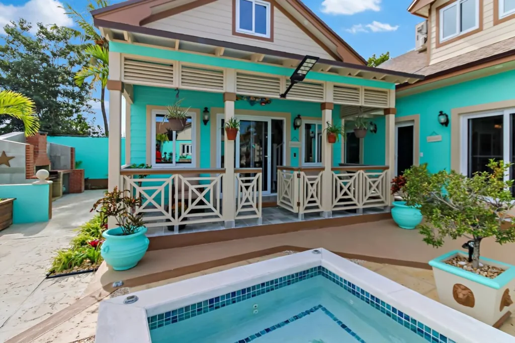Turquoise Bahamian cottage with a covered porch and potted plants, Nassau, Bahamas