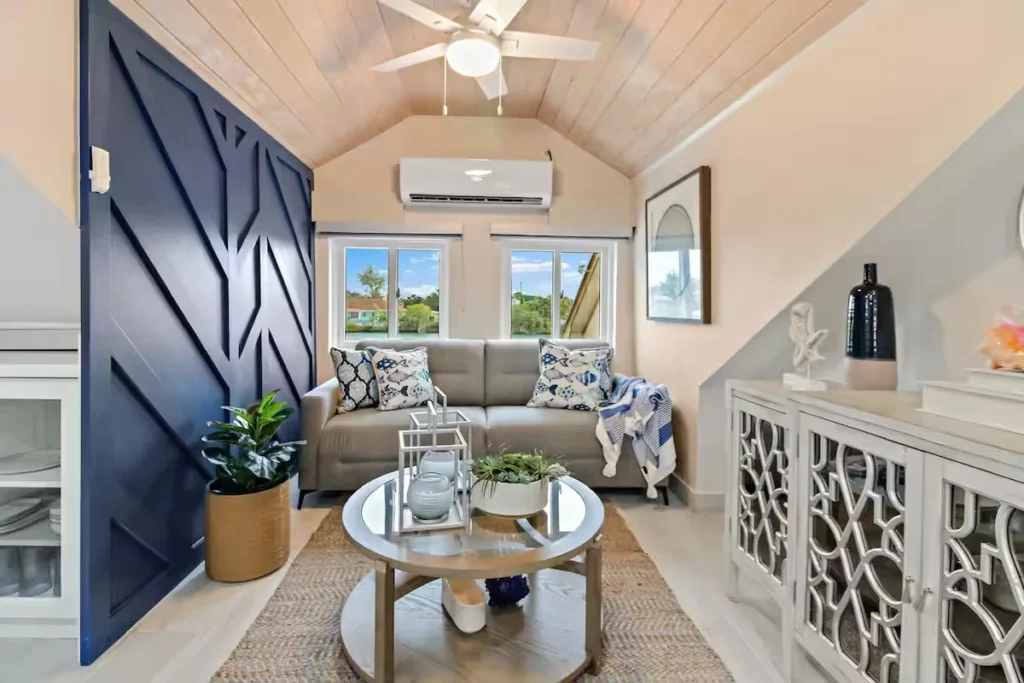 Bright coastal-style living room with a navy barn door and water-view windows, Nassau, Bahamas