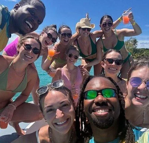Smiling group and crew take a selfie with tropical drinks aboard the boat near Nassau, Bahamas