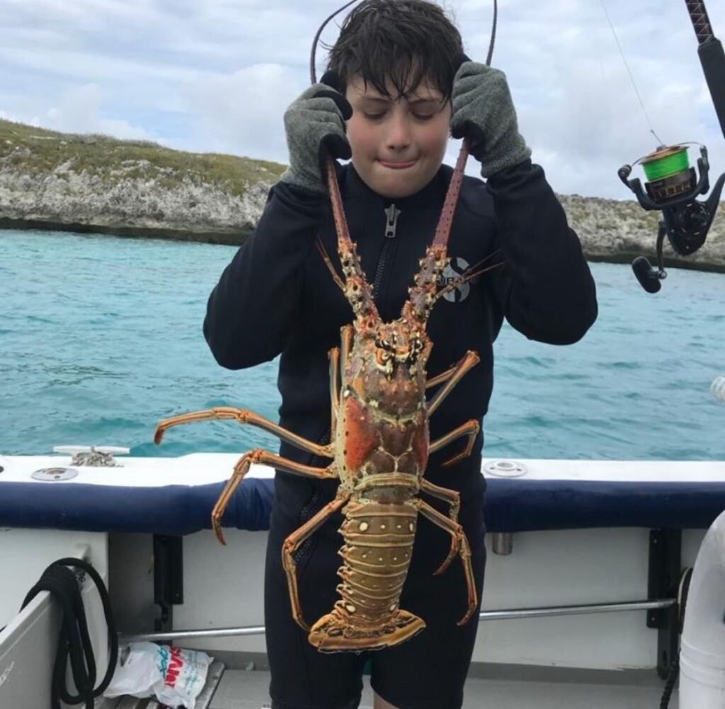 Boy holding a large spiny lobster on a private charter in Nassau, Bahamas