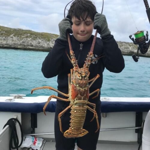 Boy holding a large spiny lobster on a private charter in Nassau, Bahamas