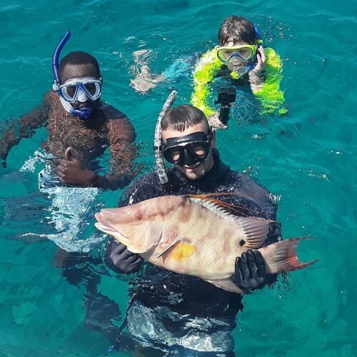 Snorkelers holding a fresh catch on a private fishing charter in Nassau, Bahamas