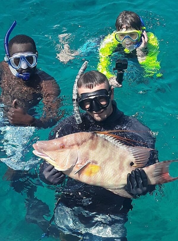 Snorkelers holding a fresh catch on a private fishing charter in Nassau, Bahamas
