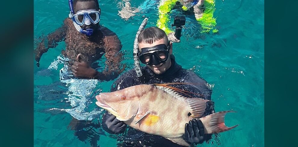 Snorkelers holding a fresh catch on a private fishing charter in Nassau, Bahamas