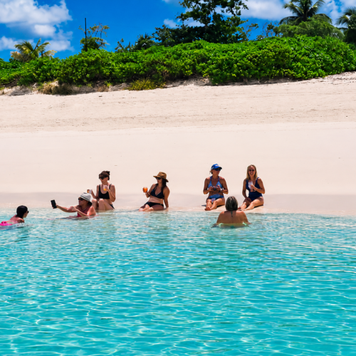 Group wading in the shallows off a pink-sand beach near Nassau, Bahamas