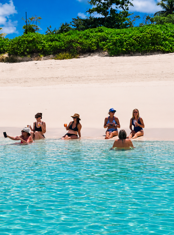 Group wading in the shallows off a pink-sand beach near Nassau, Bahamas