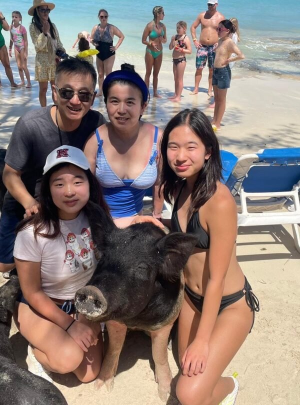 Guests posing with the swimming pigs on the beach near Nassau, Bahamas