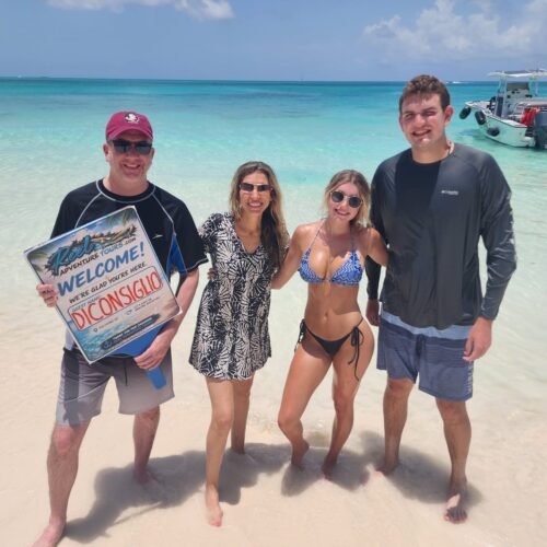 Guests holding their welcome sign on a white sand beach near Nassau