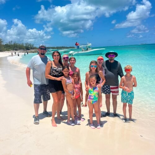 Family on a white sand beach during an island hopping tour near Nassau, Bahamas